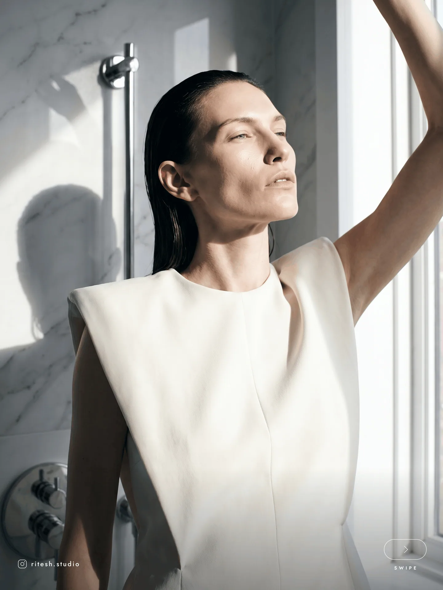 Woman in a white top reaching into soft window light