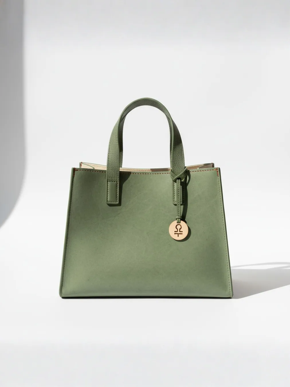 Green tote standing alone in sharp studio sunlight