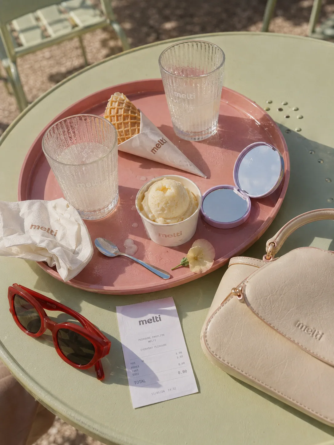 Overhead view of a pink tray with ice cream and glasses